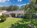 Inviting single-story home with a lush green lawn and mature trees, creating a serene and picturesque setting at 7700 Fairlawn Dr, Hudson, FL 34667