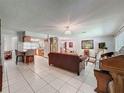 Open-concept living area features tile flooring, a comfortable sofa, and seamless flow into the dining and kitchen at 7700 Fairlawn Dr, Hudson, FL 34667