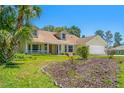 Inviting one-story home with a front porch and lush landscaping, including mature palm trees and flower beds at 10540 Noddy Tern Rd, Weeki Wachee, FL 34613