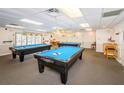 Well-lit billiards room featuring three pool tables and ample seating for a recreational space at 10641 Timber Ln, Port Richey, FL 34668