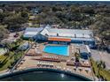 Aerial view of the community pool with ample seating and surrounding greenery, with nearby amenities at 10641 Timber Ln, Port Richey, FL 34668