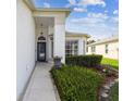 Inviting covered entryway features a decorative light fixture, well maintained landscaping, and a welcoming aesthetic at 11732 Wheatfield Loop, Hudson, FL 34667