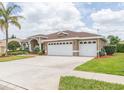Lovely one-story home with a three-car garage, fresh exterior paint, a green lawn and manicured shrubs at 13942 Talmage Loop, Hudson, FL 34667