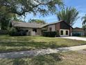 Well-maintained lawn with mature trees frames a charming single-story home with a brick chimney and two-car garage at 1412 Wexford N Dr, Palm Harbor, FL 34683