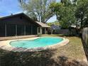 Backyard showcasing a kidney-shaped pool surrounded by lush greenery and a screened lanai for outdoor enjoyment at 1412 Wexford N Dr, Palm Harbor, FL 34683