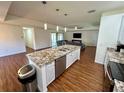 Bright kitchen island with a granite countertop, stainless steel appliances, and views into the living room at 15585 Rene Ct, Brooksville, FL 34604