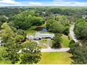 Aerial view of the home nestled on a large lot with a serene pond and lush surroundings at 2400 Commack Ct, New Port Richey, FL 34655