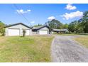 Long driveway leading to a single-story home featuring a two-car garage and a separate garage on a spacious lot at 2400 Commack Ct, New Port Richey, FL 34655