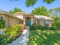 Charming home featuring a manicured lawn and a pathway leading to a vibrant blue front door at 446 Romine Ct, Spring Hill, FL 34609