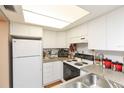 Bright kitchen featuring white cabinets, appliances, and laminate countertops for a clean and functional space at 4726 Marine Pkwy # 201, New Port Richey, FL 34652