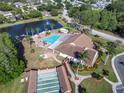 Aerial view of the community pool, clubhouse, and shuffleboard courts near a scenic pond at 4837 Prince George Cir, New Port Richey, FL 34655