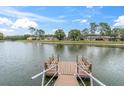 Scenic view from a wooden dock on the pond with seating and a glimpse of the community homes at 4837 Prince George Cir, New Port Richey, FL 34655