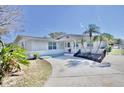 Inviting single-story home with a lush landscaped yard, palm trees and long driveway at 5404 Quist Dr, Port Richey, FL 34668