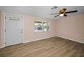 Bright living room features a ceiling fan, wood-look flooring, and a large window, creating a welcoming atmosphere at 7321 Parrot Dr, Port Richey, FL 34668