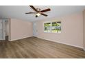 Bright living room features a ceiling fan, wood-look flooring, and a large window, creating a welcoming atmosphere at 7321 Parrot Dr, Port Richey, FL 34668