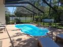 Inviting screened-in pool area with clear blue water, lounge chairs, and lush greenery at 7508 Cypress Knee Dr, Hudson, FL 34667