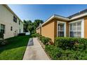 Side view of tan stucco home with manicured landscaping and walkways at 8604 Corinthian Way, New Port Richey, FL 34654