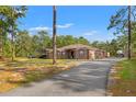 Wide angle showing long driveway leading to a one-story home with a carport and ample parking space at 9078 Birmingham Ave, Weeki Wachee, FL 34613