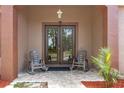 Inviting front porch with tiled flooring, double doors, rocking chairs, and manicured landscaping at 9078 Birmingham Ave, Weeki Wachee, FL 34613