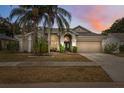 Charming home featuring a two-car garage, a well-manicured lawn, and mature palm trees at 9104 Water Hazard Dr, Hudson, FL 34667