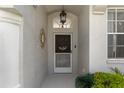 Close-up of the front door showcasing a decorative wreath, stylish light fixture, and transom window for added light at 9400 New Orleans Dr, Weeki Wachee, FL 34613