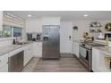 Bright kitchen featuring white cabinets, stainless steel appliances, granite countertops, and wood-look floors at 12708 River Mill Dr, Hudson, FL 34667