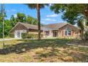 Charming one-story home with a brick and siding facade, attached garage, and mature trees shading the front yard at 13469 Pia Ct, Spring Hill, FL 34609
