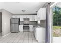Bright kitchen with white cabinets, stainless appliances, granite counters, and a sliding door leading to the backyard at 27198 Simona Ave, Brooksville, FL 34602