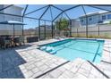 Relaxing screened-in pool with pavers, lounge chairs, dining table, and lush landscaping for ultimate outdoor enjoyment at 2815 Dudley Ave, Odessa, FL 33556