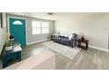Cozy living room showcases modern flooring and a comfortable sofa adjacent to an inviting turquoise front door at 3545 Oxford Dr, Holiday, FL 34691