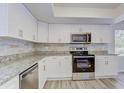 Modern kitchen features white cabinets, stainless steel appliances, and a stylish backsplash at 37733 14Th Ave, Zephyrhills, FL 33542