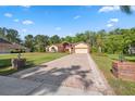 A spacious single-story home with a brick driveway and lush landscaping in a serene setting at 4469 Lake In The Woods Dr, Spring Hill, FL 34607
