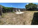 A spacious backyard enclosed by a wooden fence features a stone sitting area and lush greenery at 9104 Lido Ln, Port Richey, FL 34668