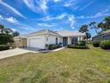 Attractive single-story home with a well-manicured lawn, mature trees, and a two-car garage on a sunny day at 9237 Penelope Dr, Weeki Wachee, FL 34613