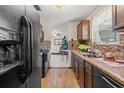 Kitchen with wood cabinets, tile backsplash, and modern appliances that flows to the living room at 9640 Northcliffe Blvd, Spring Hill, FL 34608