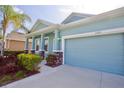A charming light-blue home featuring a two-car garage, decorative pillars, and lush landscaping at 11041 Paradise Point Way, New Port Richey, FL 34654
