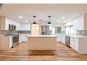 Bright kitchen features white cabinets, stainless steel appliances, island with quartz countertop, and stylish pendant lighting at 12709 Castleberry Ct, Hudson, FL 34667
