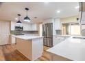 Bright kitchen features white cabinets, stainless steel appliances, island with quartz countertop, and stylish pendant lighting at 12709 Castleberry Ct, Hudson, FL 34667