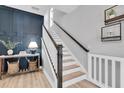 Stylish staircase with white risers, wooden handrail, and accent wall with modern decor at 12889 Burns Dr, Odessa, FL 33556