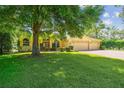 Lovely yellow single-story home with well-kept lawn, neat shrubbery, and three car garage at 18502 Winding Oaks Blvd, Hudson, FL 34667