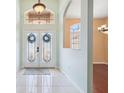 Inviting foyer with decorative glass double doors and light-colored tile flooring at 4080 Gevalia Dr, Brooksville, FL 34604