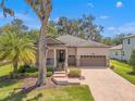 Charming single-Gathering home featuring a brick driveway, two-car garage, a cozy porch, and manicured landscaping at 4910 Southern Valley Loop, Brooksville, FL 34601
