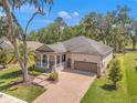 Charming single-Gathering home featuring a brick driveway, two-car garage, a cozy porch, and manicured landscaping at 4910 Southern Valley Loop, Brooksville, FL 34601