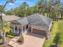 Charming single-Gathering home featuring a brick driveway, two-car garage, a cozy porch, and manicured landscaping at 4910 Southern Valley Loop, Brooksville, FL 34601
