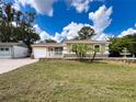 Well-maintained front yard with lush lawn, palm trees, water feature, and inviting curb appeal at 5147 Larch Ln, New Port Richey, FL 34653