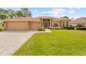 Charming home with manicured lawn, brick accents, a brick paver driveway, and a two-car garage at 5164 Golf Club Ln, Spring Hill, FL 34609