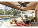 Inviting screened lanai featuring comfortable seating, a ceiling fan, and a view of the sparkling pool and lush backyard at 5638 Hereford Dr, New Port Richey, FL 34655