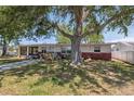 Charming single-story home with a brick facade, screened in porch, and a spacious front yard with a large tree at 6521 Boatyard Dr, Hudson, FL 34667