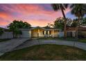 Cozy home with a well-maintained front yard, driveway, and colorful sky at dusk at 7235 Astor Dr, New Port Richey, FL 34652