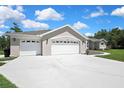 Three-car garage with white doors, concrete driveway, and partial view of the landscaped front yard at 7495 Birdland Cres, Spring Hill, FL 34607